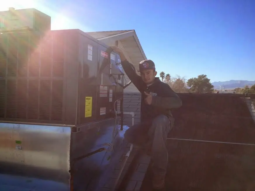 HVAC technician performing Air Duct Repair on a rooftop unit in Peoria Heights